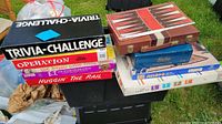 Stack of boxed board games showing titles: Trivia Challenge, Operation, The Game of Life, E.T.: The Extra-Terrestrial, Huggin' The Rail