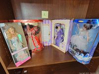 Four boxed Barbie dolls displayed on a shelf, showing full front view of each doll box.