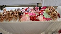 Wide view of Barbie and Ken dolls laid out nude on table with numerous pieces of clothing and shoes laid out between the dolls.