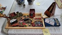 Full view of all items including wooden tray with vehicles, metronome, dominoes sets, and lighter.