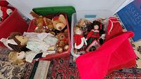 Overview of two storage bins showing plush animals including teddy bears and dolls along with large red felt Santa Claus present bags.