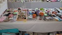 Wide view of jewelry making supplies on a table including ribbons, beads, and findings