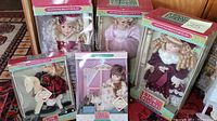 Group photo showing five boxed Classic Treasures porcelain dolls with varying styles and sizes, displaying the packaging and labeling on each box.