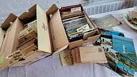 Two open cardboard boxes containing sorted postcards with divider tabs labeled 'Early Fancy Postcards 1900s', 'German Easter', '1920s, 30s, 40s' and a second box of assorted cards