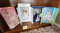 Four boxed Barbie dolls on a shelf: Millennium Princess, Blushing Bride, Ballet Masquerade, Nutcracker Sugar Fairy.