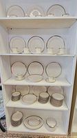 Multiple shelves with various pieces of Viletta Silver Leaf china including plates, cups, saucers, bowls, and covered serving dishes arranged for display