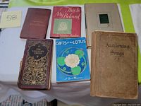 Top view of six vintage books arranged on a white tablecloth including hymnals and prayer books.