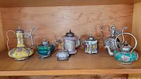 Seven wine pots displayed side by side on a wooden shelf