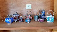 Overview of all nine Chinese wine pots arranged on wooden shelf