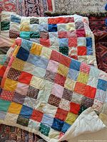 Full view of the patchwork quilt showing multi-colored squares arranged in a grid pattern with visible stains and texture details.
