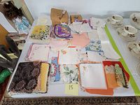 Top-down view of collection laid out on table showing handkerchiefs and napkins with a small wicker basket, wooden box, and Christmas cards grouped together.