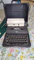 Vintage Royal Quiet Deluxe manual typewriter in open black hard case with typed paper in platen.