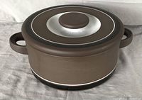 Brown Hornsea Vitramic casserole pot with concentric circle design lid, two handles, viewed closed on grey background.