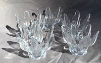 Photo showing five clear art glass candleholders with petal-like upward curved shapes.