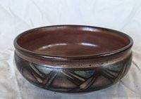 Side view of round pottery bowl showing brown glaze and abstract decorative band.