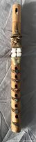 Full view of the bamboo flute with ceramic facial decoration and stone accents showing the length and overall design.