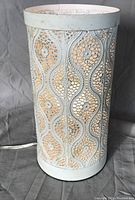 Side view of the lamp showing intricate filigree pattern and antiqued white finish.