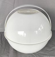 Closed view of the white spherical picnic basket with top air vents and handle, showing the basket intact and standing upright.