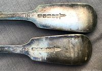 Close-up of hallmarks stamped on the back of both forks showing letters and symbols confirming English silver origin.