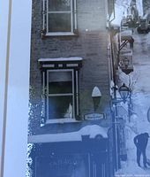 Close-up detail of the black and white photograph showing snowy street scene with vintage lanterns and pedestrians, titled 'Sous-le-Fort' Quebec City.