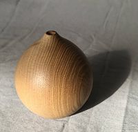 Studio artisan bud vase, wooden rounded form with narrow opening, showing natural wood grain and smooth finish.