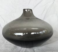 Side view of the smoke grey vase showing its round shape and narrow neck.