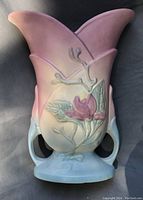 Front view showing pink and purple flower relief, flared rim and dual handles.