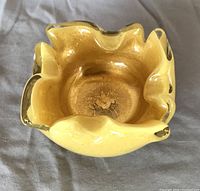 Top view of yellow Murano glass ashtray showing ruffled edges and embedded gold flakes inside the glass.