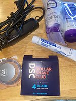 Electric hair clippers with cord surrounded by skincare tubes and shaving cartridges