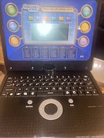 Front view of the Discovery Kids Teach & Talk Exploration Laptop showing keyboard and screen with colored activity buttons around the screen