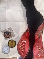 Golf club cover in black and red, two golf tokens, and one golf ball shown on white background