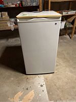 Front facing photo of white GE bar-sized fridge with top freezer compartment