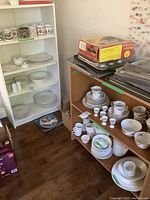 Full view of white and brown bookcases with dishes and bakeware on shelves