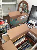 Three open boxes packed with books of various topics such as nature, aircraft, and railroads.