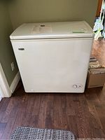 Full exterior front view of white chest freezer on hardwood floor