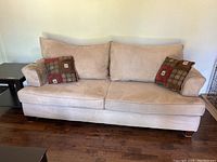 Front view of large beige couch with two seat cushions, two back cushions, and two decorative pillows with geometric patterns.