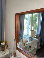 Side angle showing the wood frame of the mirror and some surrounding room details.