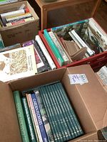 Boxes and crate containing various gardening books including Encyclopedia of Gardening and other titles, with wooden bookends visible.