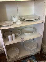 Multiple plates, salt & pepper shakers, small serving dishes on white shelves showing different sizes and types of dishes.