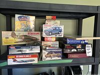 Shelf holding various boxed model kits and games, showing collection and condition of lot.