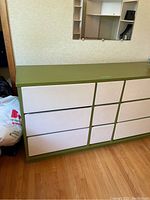 Front angle showing the left side and top of the avocado green and white retro dresser with 9 drawers.
