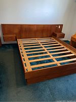 Full frontal view of teak veneer platform bed frame with slatted support and integrated nightstands
