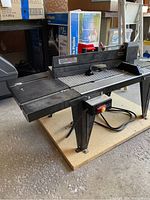 Full side view of black Craftsman router table mounted on MDF board with power switch and electrical cord visible.