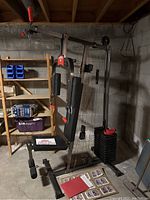 York Compact One 901 home gym weight lifting machine shown assembled in basement with instructional posters and two hand weights on floor nearby.