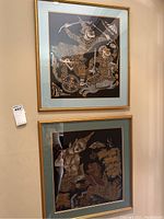 Two framed Asian art prints hanging on wall with detailed gold designs on black background, in gold frames with blue mats.