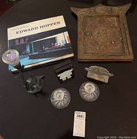 Full view of all items including Edward Hopper art book, metal Inukshuk, black metal swan candleholder, wooden plaque with metal inlay, and two glass candleholders.