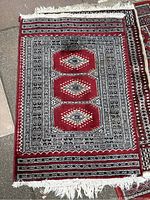 Full view of one red carpet with three diamond geometric shapes and detailed patterned borders and fringes