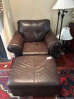 Front view of brown leather sofa chair with matching ottoman on a patterned rug