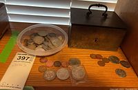 Metal box closed with handle on top, plastic container with coins and loose coins around