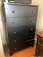 Front view of the 5 drawer black dresser showing metal knobs
